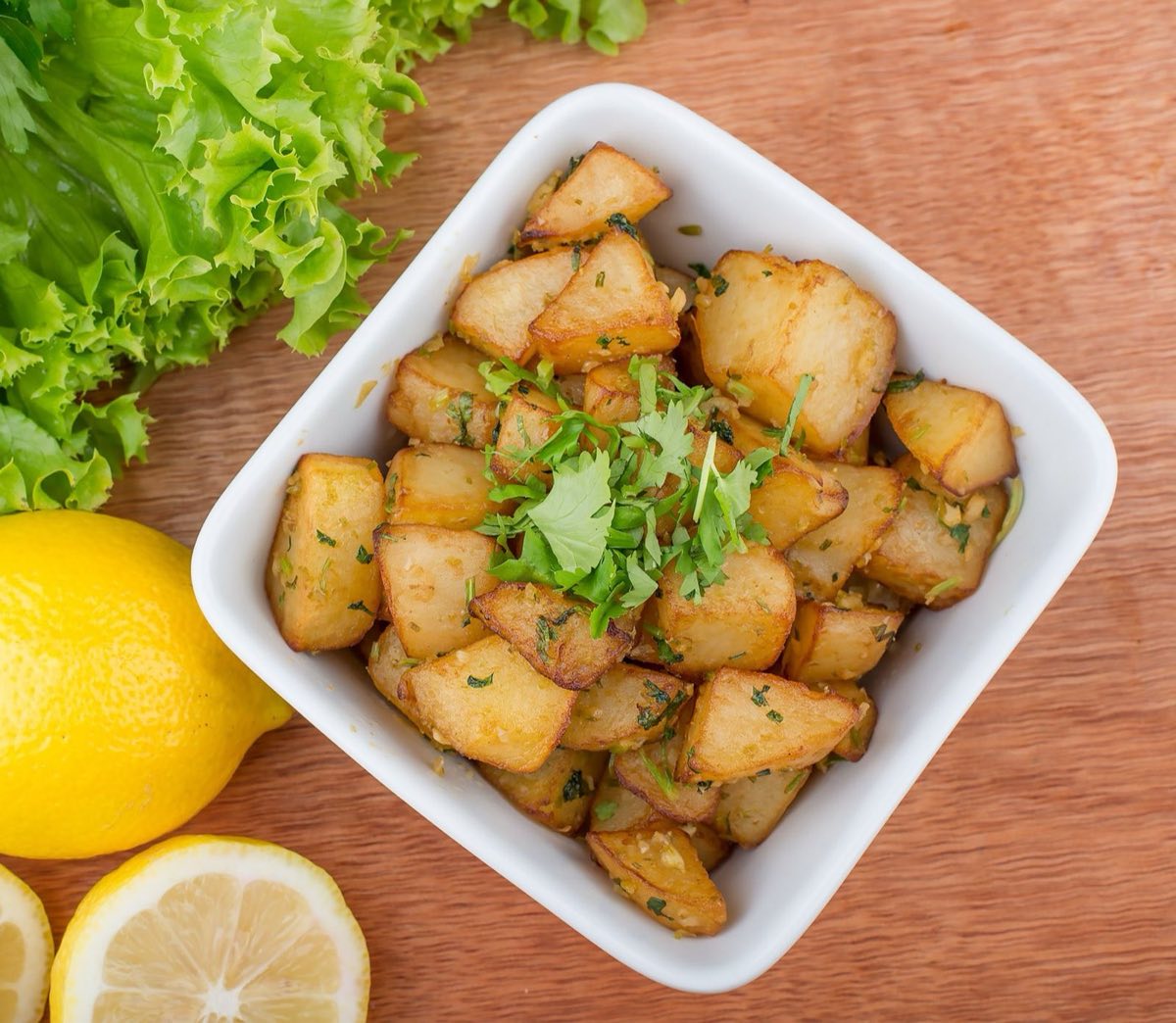 Batata Harra — Crispy roasted potatoes tossed in a volcanic mixture of fresh coriander, red chili, garlic, and a sharp