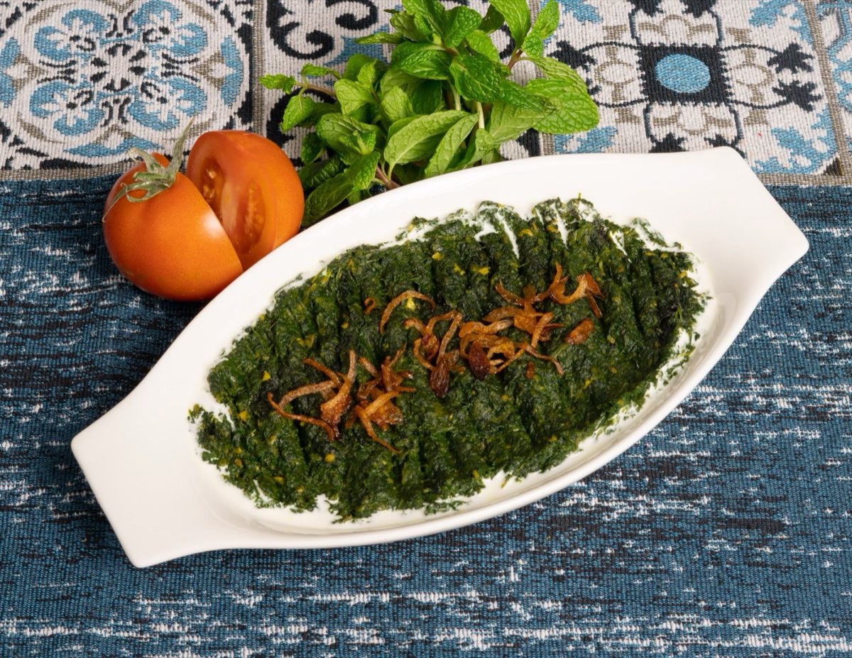Hindbeh bil Zeit — Bitter wild chicory leaves sautéed until silky, heaped with a mountain of crisp caramelized onions, and
