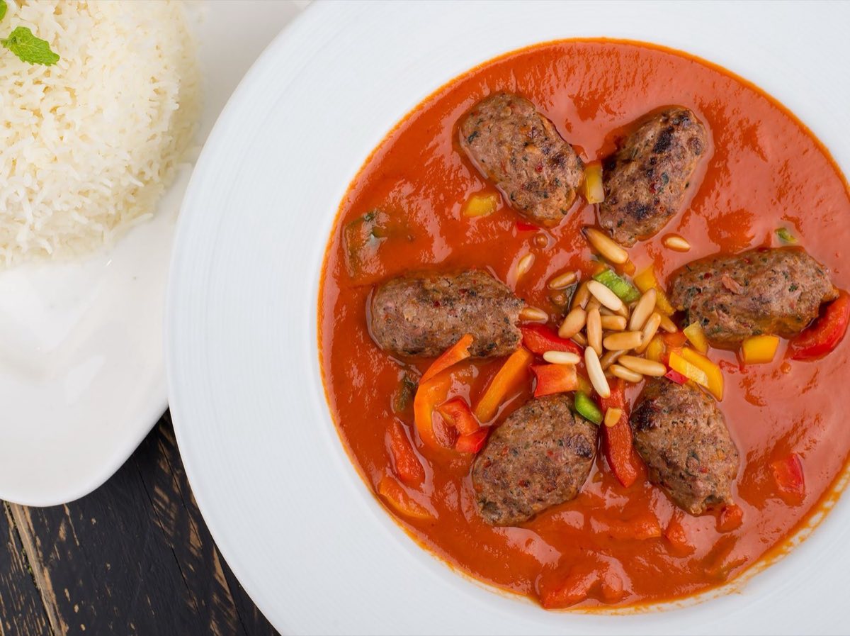 Kafta bil Bandora — Oval patties of spiced kafta nested in a fragrant tomato sauce with sliced potatoes, all slow-baked in one