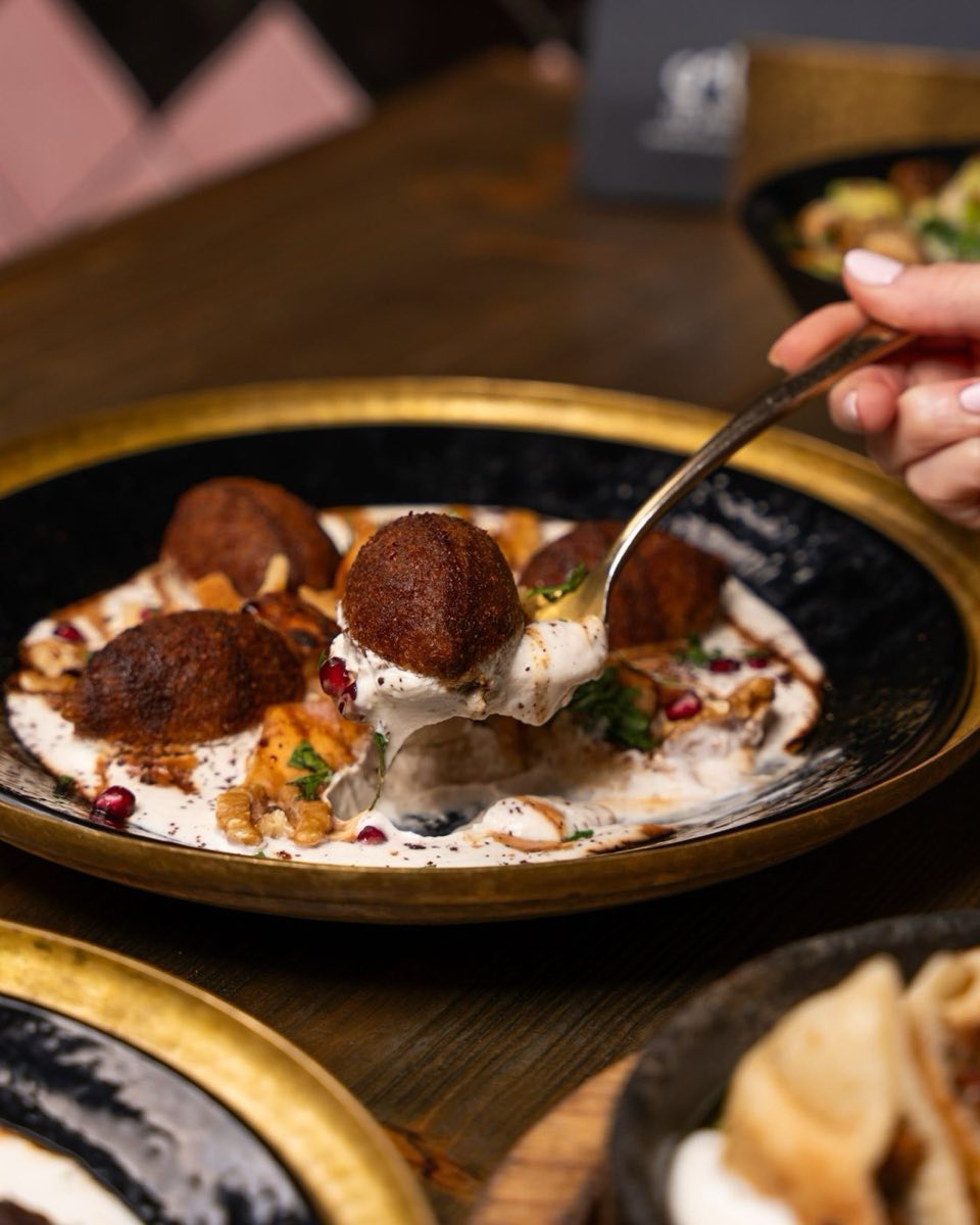 Idlib Kibbeh in Sheep's Milk Yogurt Sauce — Torpedo-shaped kibbeh shells cooked directly in a stabilized sheep's milk yogurt sauce fragrant with dried