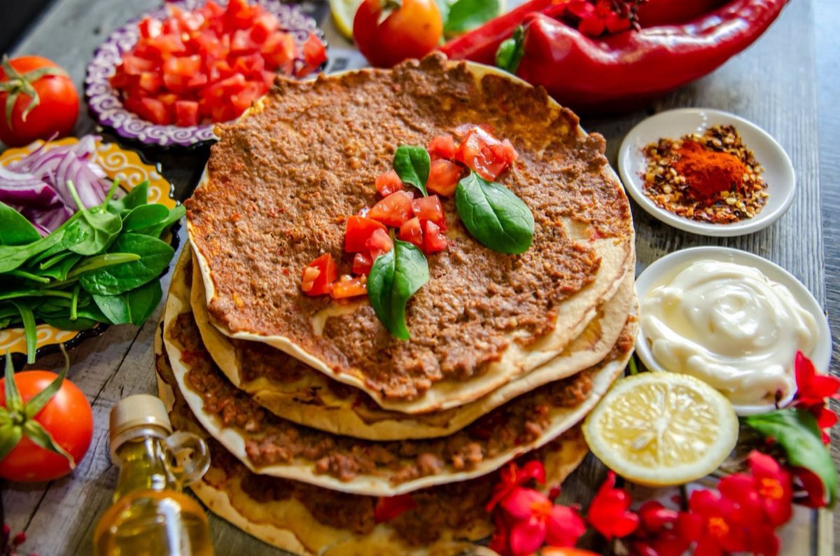 Lahm bi Ajeen — Thin, crisp flatbread topped with a mixture of spiced lamb, tomato, and pomegranate molasses