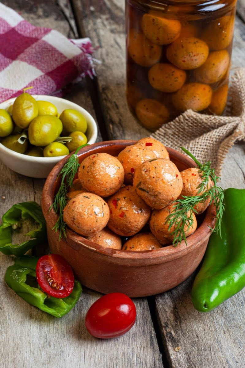 Lebneh Balls in Olive Oil — Dense, tangy labneh rolled into walnut-sized balls, coated in dried herbs and chili, and preserved in good