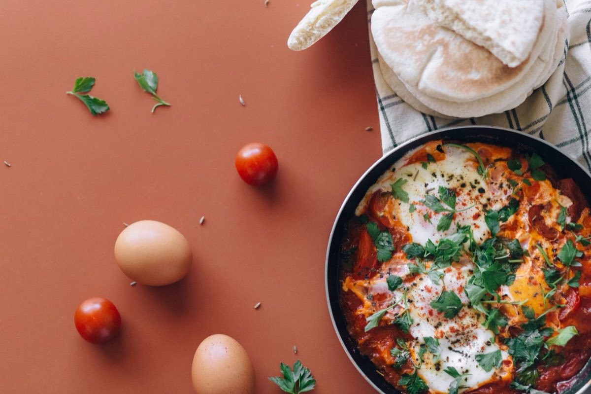 Qalayet Bandora — Sautéed Tomatoes with Eggs — Ripe tomatoes crushed into a pan with olive oil and garlic until they collapse into a thick, jammy sauce
