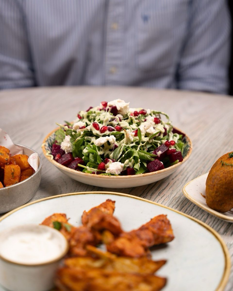Salatet Jarjir — Wild-style arugula tossed with toasted walnuts, fresh pomegranate, shaved Parmesan optional