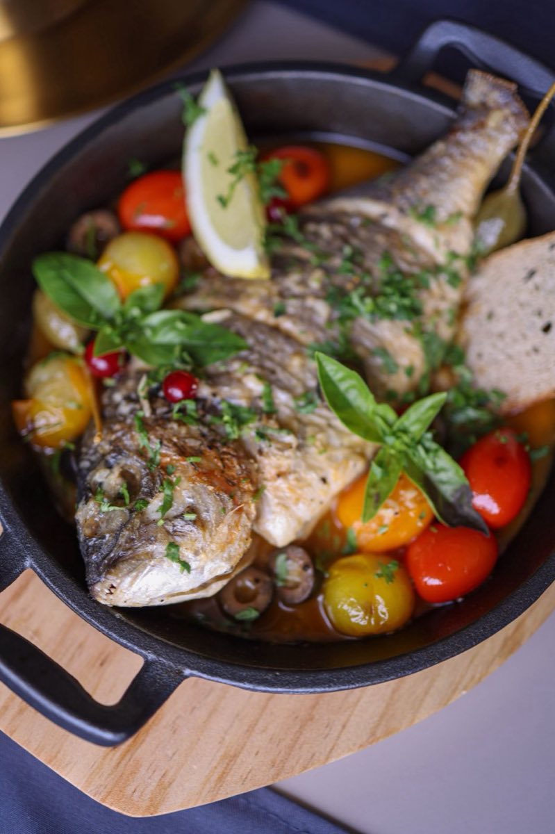 Samak bil Forn — Oven-Baked Fish with Onion and Tomato — A whole sea bass or sea bream baked over a bed of caramelized onions, sliced tomatoes, and lemon slices until
