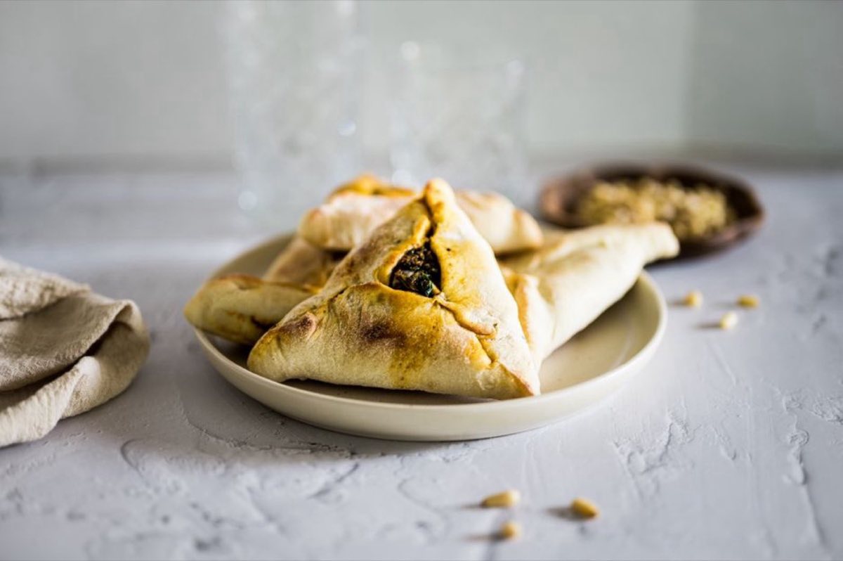Spinach Fatayer — Delicate triangular pastries pinched shut around a filling of wilted spinach, sumac, onion, and lemon