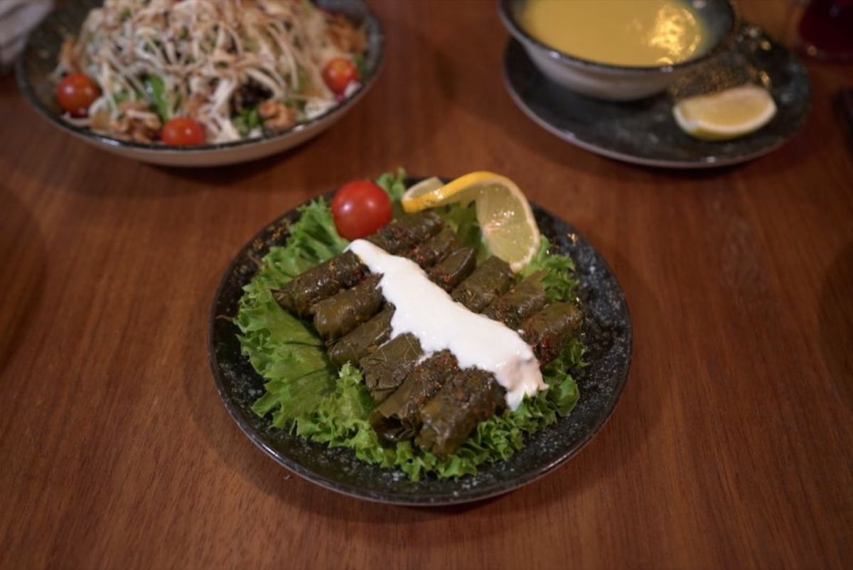 Waraq Enab bil Lahmeh — Idlib Style with Yogurt-Mint — Grape leaves rolled around rice and beef and simmered with garlic, served the Idlib way